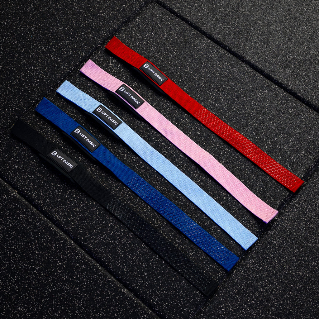 Set of lifting straps in red, blue, pink, and black on a textured black surface.